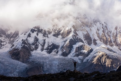 A man in grey mountains covered by snow hands near the top of the hill's silhouette photographs
